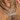 Close-up of neck with layered necklaces, including a cross and name pendant.