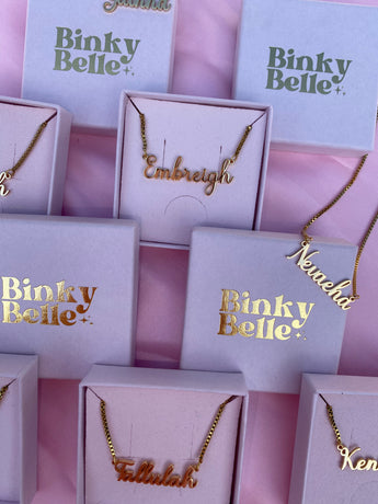 Gold necklaces in Binky Belle boxes on a pink background