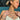 Woman with blonde hair in a bun wearing layered gold and silver necklaces, including a “Melissa” name necklace, heart charm necklace, and floral pendant; she also wears stacked bracelets, a delicate silver hand chain, and mixed-metal rings while relaxing by a pool in sunlight