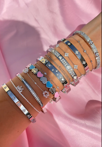 Multiple bracelets on a wrist against a pink fabric background