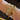Gold bracelet with name charms on a wrist against a dark background