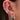 Close-up of an ear with multiple earrings including hoops, studs, and a clip-on earring.