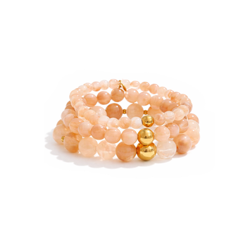 Stack of beige-colored beaded bracelets with gold accents on a white background
