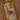 Close-up of gold tarot necklace featuring ‘The Lovers’ card with a pink heart, crystal stars, and gold hands on a mother-of-pearl background